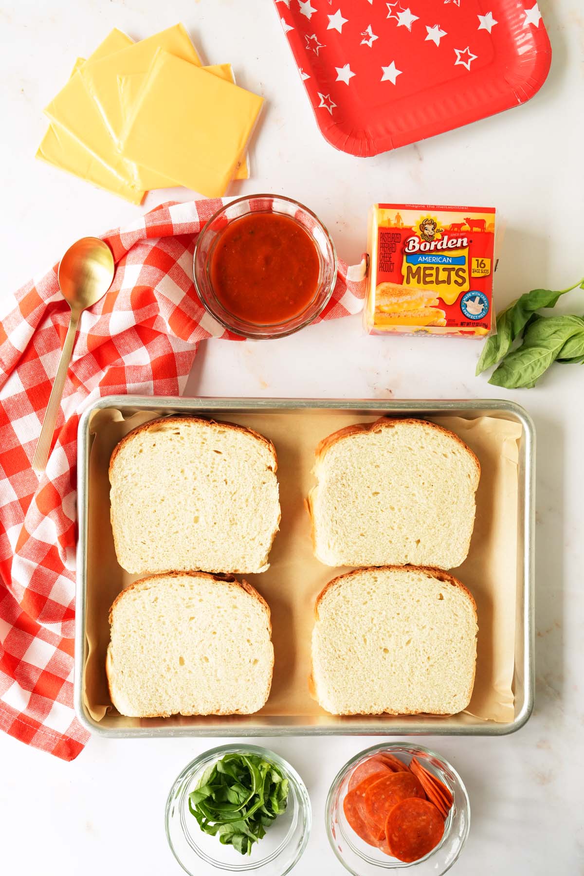 Pepperoni Grilled cheese ingredients featuring four slices of white bread on a red pan.
