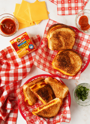 Pepperoni Grilled cheese sandwiches in red checkered baskets with ingredients nearby.