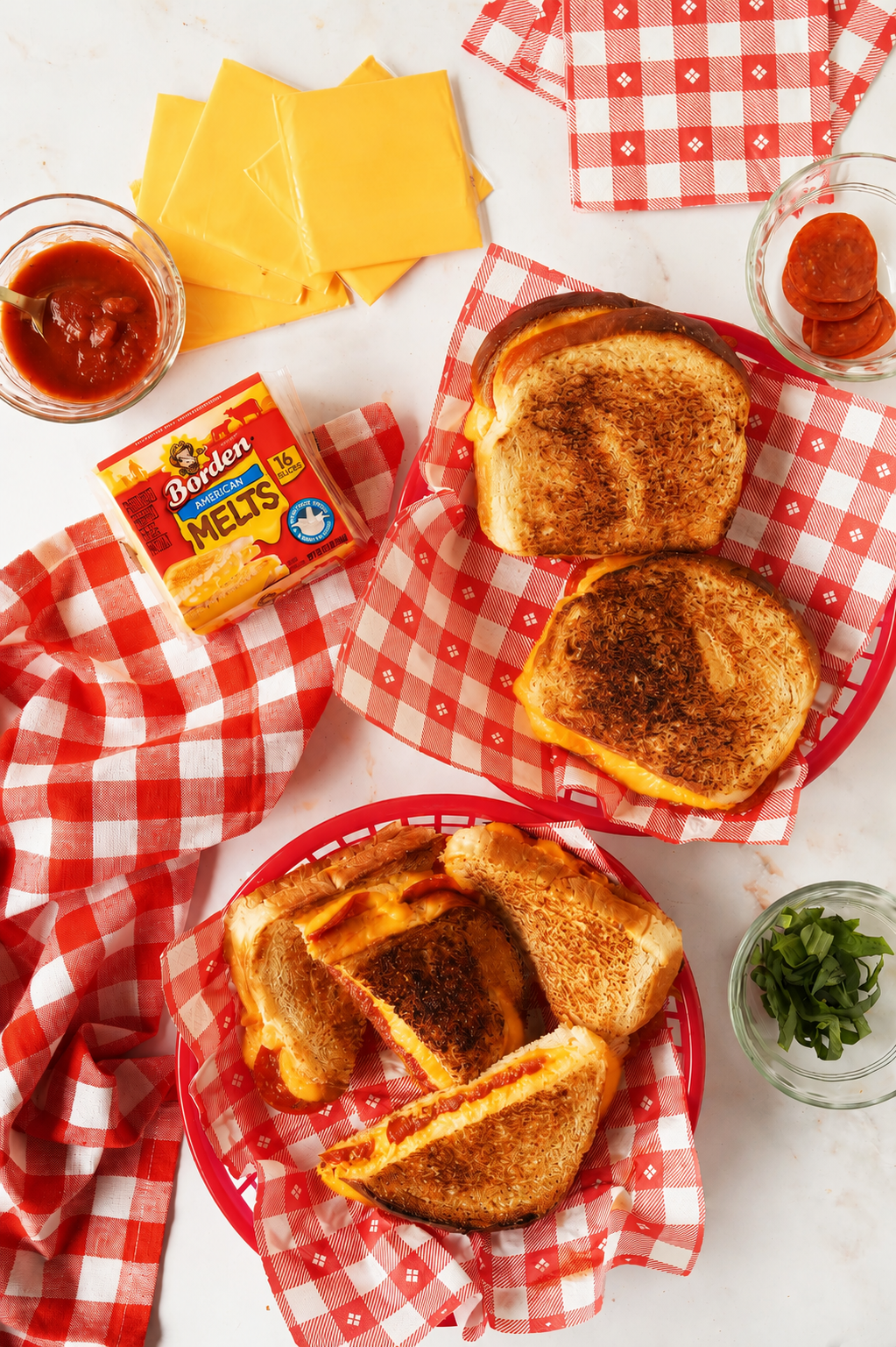 Pepperoni Grilled cheese sandwiches in red checkered baskets with ingredients nearby.