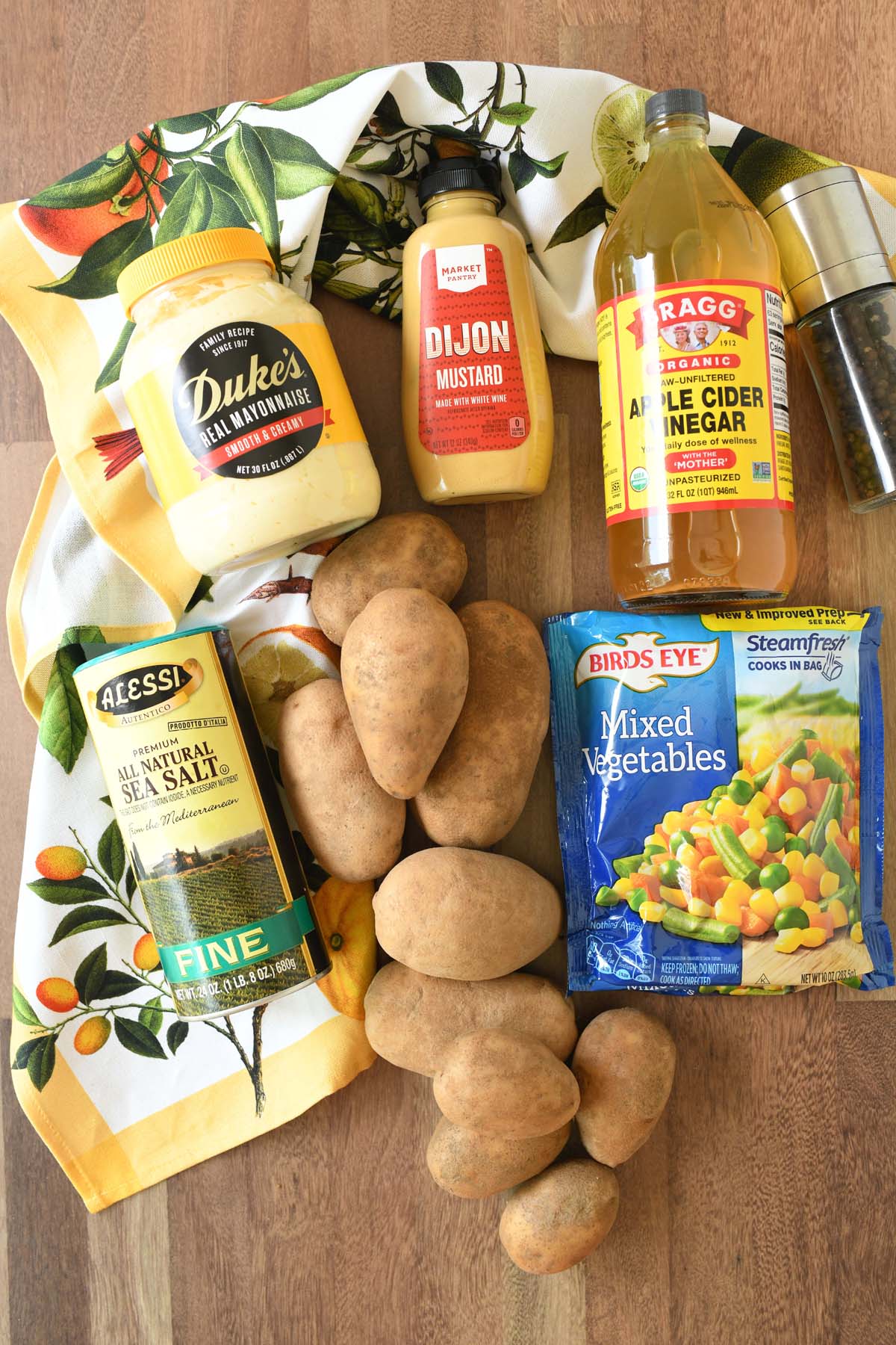 Brazilian potato salad ingredients on a wooden table with a citrus napkin.