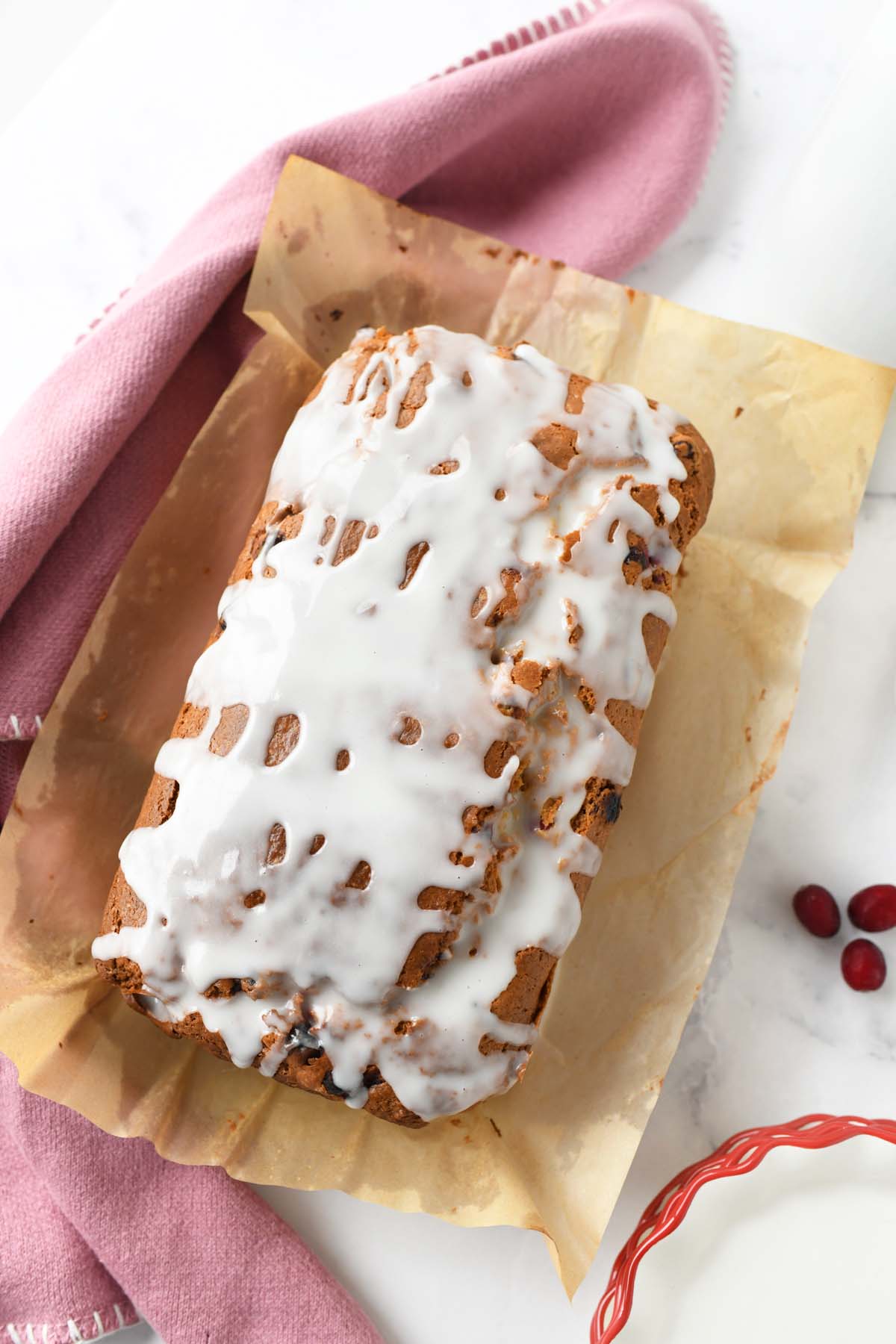 Top down shot of iced cranberry loaf near a pink napkin.