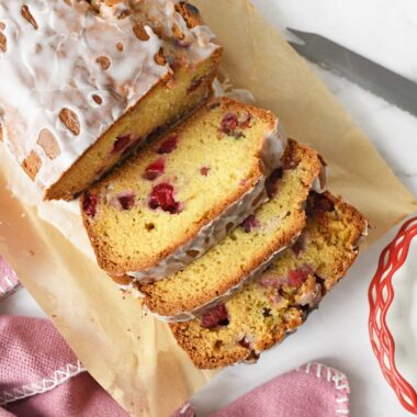 Sliced cranberry loaf near a pink napkin, and knife.