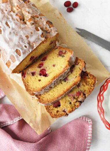 Sliced cranberry loaf near a pink napkin, and knife.