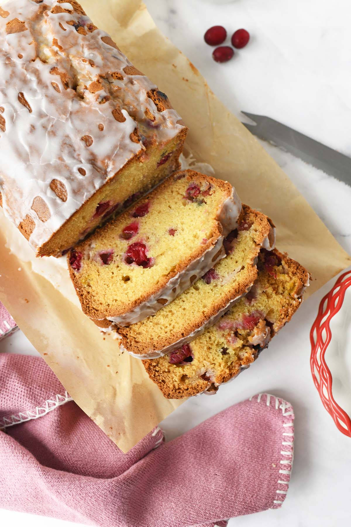 Sliced cranberry loaf near a pink napkin, and knife.