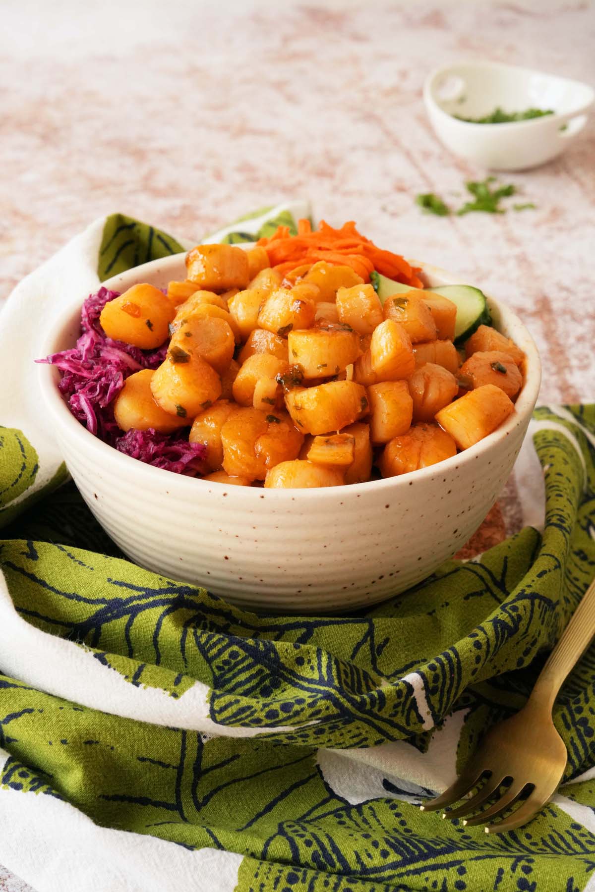 A colorful Gochujang scallop bowl near a green fern napkin.