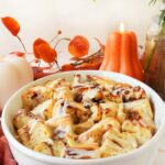 A comforting bowl of apple cinnamon casserole with fall candles and florals in the background.