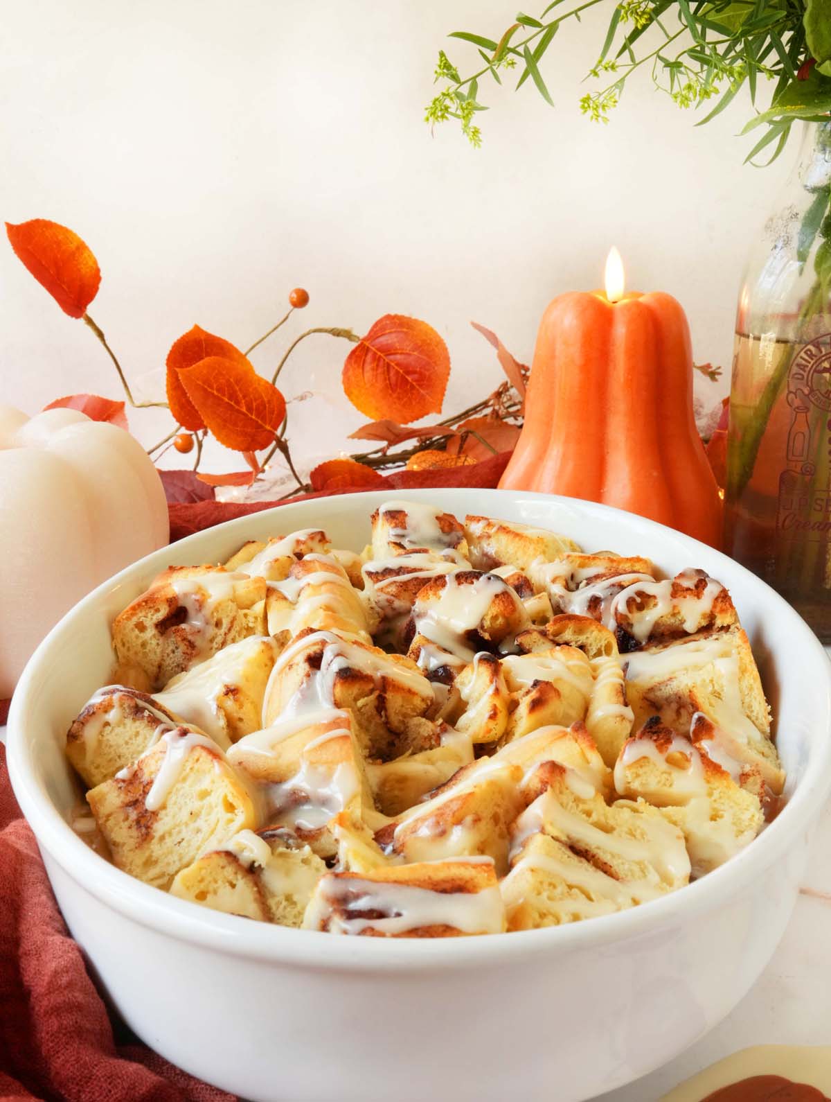 A comforting bowl of apple cinnamon casserole with fall candles and florals in the background.