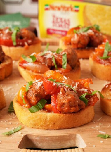 Parsley-topped Texas Toasts with sausage, onions, and peppers on top near a box of New York Bakery Texas Toasts.