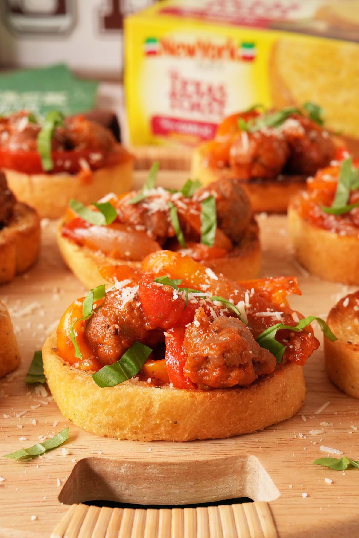 Parsley-topped Texas Toasts with sausage, onions, and peppers on top near a box of New York Bakery Texas Toasts.